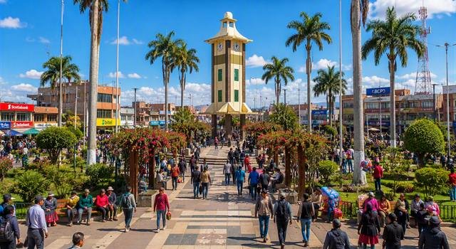 Plaza principal de Juliaca con su torre del reloj, palmeras y visitantes caminando.