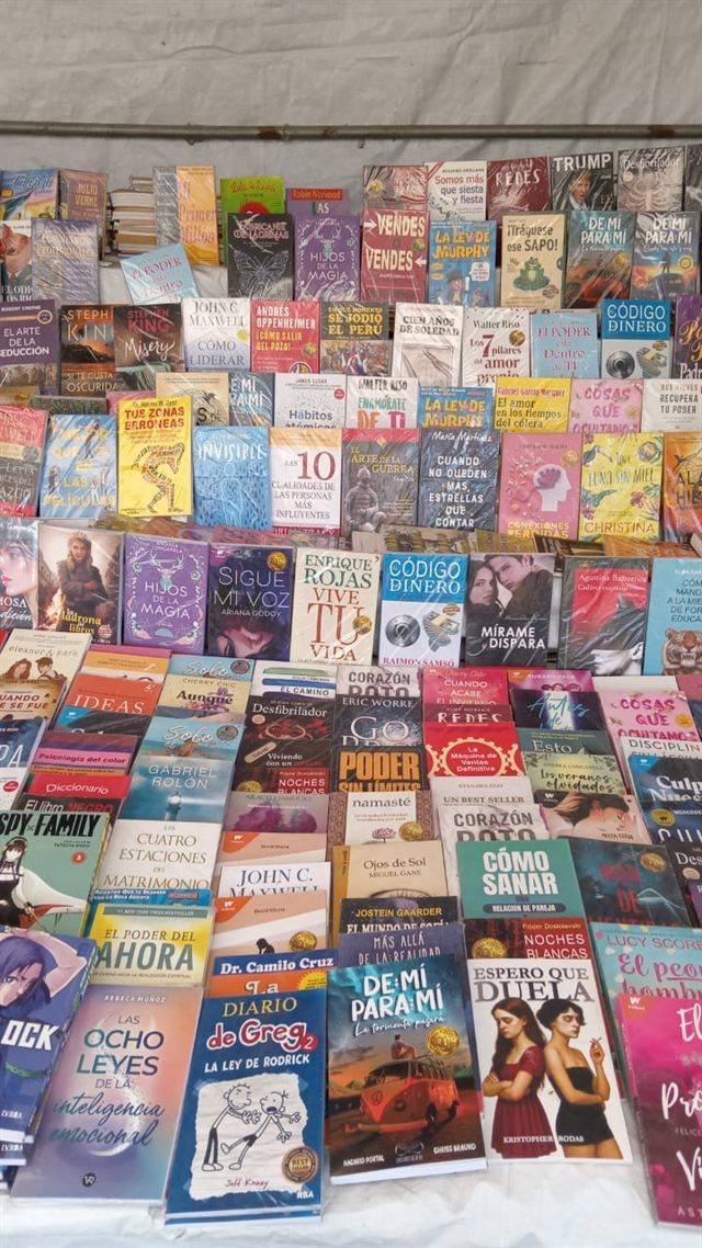 Mesa de feria cubierta de libros de novela, superación personal y literatura juvenil.